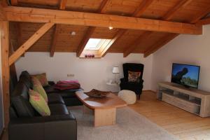 Una sala de estar con un sofá negro y un televisor. en Landhaus Bernecker, Bay.W., en Rinchnach