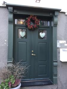 a green door with a wreath and hearts on it at Holsthuset Losji in Grimstad