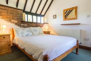 a bedroom with a bed and two lamps and a stone wall at Three Gates Farm Holiday Cottages in Huntsham +44 photos