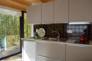 cocina con armarios blancos, fregadero y ventana en Bamboo Guest House, en Águeda