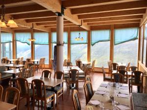 ein Esszimmer mit Tischen, Stühlen und Fenstern in der Unterkunft Panoramarestaurant Kaiser Franz-Josefs-Höhe in Heiligenblut