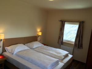 Schlafzimmer mit einem Bett mit weißer Bettwäsche und einem Fenster in der Unterkunft Panoramarestaurant Kaiser Franz-Josefs-Höhe in Heiligenblut