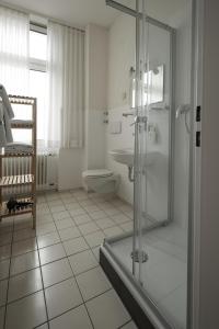 a bathroom with a shower and a toilet and a sink at Hotel Burgfeld in Kassel