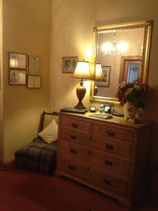 a bedroom with a dresser with a lamp and a mirror at Whitehouse Country House in Saint Boswells