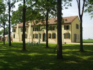 una grande casa bianca con alberi in primo piano di Agriturismo Principe Pio a Crespino