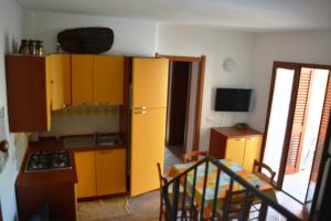 een keuken met gele kasten en een tafel en een trap bij Recidence il gabbiano in Valledoria