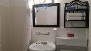 a white bathroom with a sink and a mirror at American Inn Motel Canon City in Canon City +4 photos