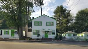 a white house with green accents on a street at Lighthouse Cabins in Old Orchard Beach