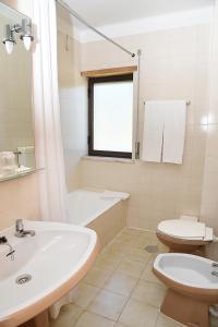 a white bathroom with a sink and a toilet at Hotel Val Flores in Valença
