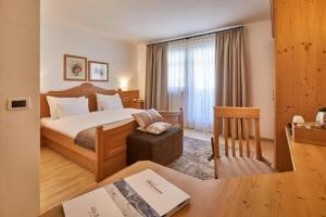 a hotel room with a bed and a desk with a chair at Ciasa Verena in Corvara in Badia