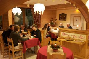 un grupo de personas sentadas en mesas en un restaurante en Le Soleil d'Or en La Giettaz