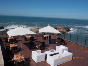 a patio with tables and umbrellas overlooking the ocean at Riad Mimouna in Essaouira