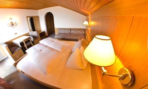 a bedroom with a bed with a lamp and a couch at Pension Obertaberhof in Schenna