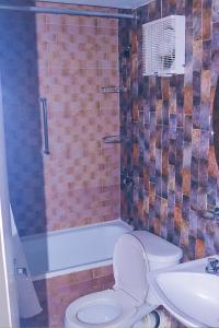 a bathroom with a toilet and a tub and a sink at Surf Turf Two Bedroom Suite At Turtle Towers in Ocho Rios +9 photos