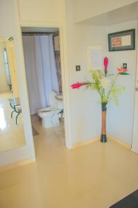 een badkamer met een toilet en een vaas met bloemen erin bij Surf Turf Two Bedroom Suite At Turtle Towers in Ocho Rios