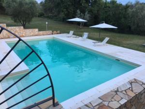 een zwembad met twee stoelen en twee parasols bij Villa Saturnia - Piscina Privata - 9' dalle Terme in Capanne
