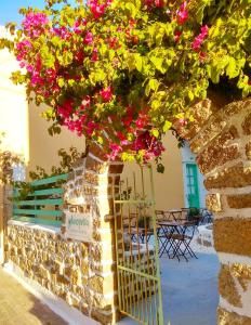 una pared de piedra con flores rosas y una puerta en Galanopetra RHODES GREECE, en Rodas