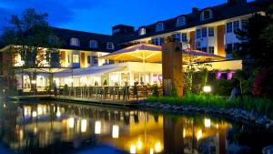 a hotel with a pond in front of it at night at Wellings Parkhotel in Kamp-Lintfort