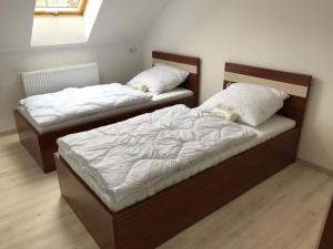 2 bedden in een slaapkamer met witte lakens bij Kálvária Apartman in Baja