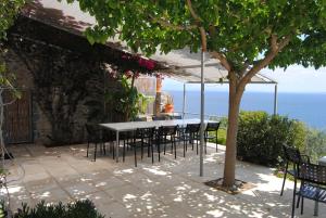 una mesa y sillas en un patio con vistas al océano en Leonidionhouses - The Ogra House, en Leonidio