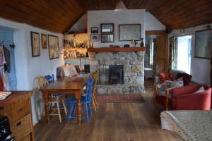 sala de estar con mesa y chimenea de piedra en Marsh Cottage F91 N4A9 en Moneygold