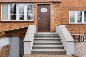 a brick building with stairs leading to a brown door at 5 pokoi in Gdańsk