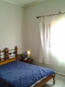 a bedroom with a bed with a blue blanket and a window at Casa Central Ribeirao in Ribeirão Preto