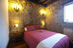 a bedroom with a bed and a stone wall at Agroturismo Izarre in Errezil