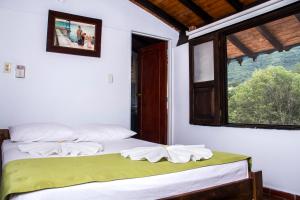 two beds in a room with a window at Hotel Campestre La Ribera del Fonce in San Gil