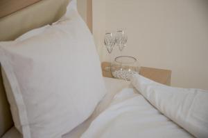 a bed with white sheets and a white pillow and chandelier at Apart Hotel Apolonia Palace in Sinemorets
