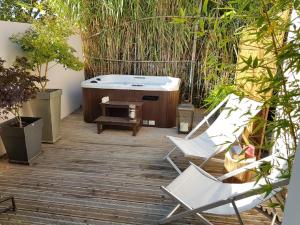 - Terraza con 2 sillas y bañera en Gîte Les Roseaux Spa extérieur privatif inclus, en Moussan