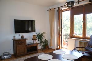 a living room with a flat screen tv and a table at Apartament w Kozubniku z widokiem na góry in Porąbka