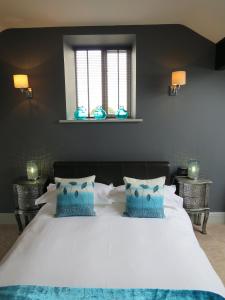 a bedroom with a large white bed with blue pillows at The Courtyard Cottage, Timble near Harrogate in Timble