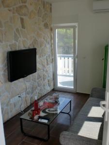 ein Wohnzimmer mit einem TV und einem Couchtisch in der Unterkunft Villa Santa Barbara in Vrsi