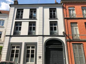 une maison blanche avec une porte et des fenêtres noires dans l'établissement Victoria's House, à Lille