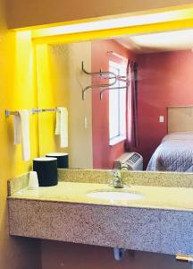 a bathroom with a sink and a bed and a mirror at Camino Real Motel in San Antonio