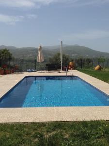 a swimming pool with a table and an umbrella at Villa Spiti Louloudis in Spílion