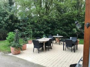 a patio with tables and chairs and trees at La Nicoulette in Gapennes
