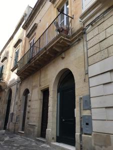 a building with a black door and a balcony at La Suite di Martina in Lecce