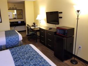 a hotel room with a bed and a desk with a television at Shining Light Inn & Suites in Kissimmee