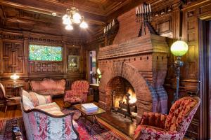 a living room with a brick fireplace with two chairs at Cedar Crest Inn in Asheville