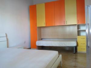una camera con due letti e armadi arancioni e gialli di La Baia Apartments by My Home Apulia a Torre Lapillo