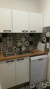 a kitchen with white cabinets and a stove top oven at Appartement les Regrattiers in Poitiers