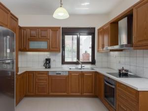 cocina con armarios de madera, fregadero y ventana en The Lake House, en Mouríon