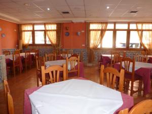 a dining room with tables and chairs and windows at Hostal Cortés in Garrucha