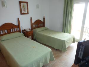 a bedroom with two beds and a tv and a window at Hostal Cortés in Garrucha