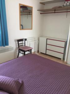 1 dormitorio con 1 cama de color púrpura y 1 silla en Appartement dans Les jardins de Phoebus en Gruissan