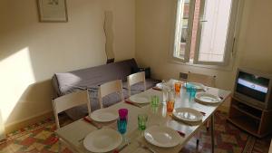 uma mesa com cadeiras e pratos e uma televisão em Chez'Artistes em Argelès-sur-Mer