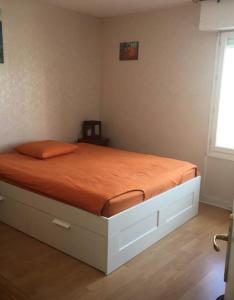 Ce lit se trouve dans une chambre dotée d'une couverture orange. dans l'établissement une chambre ENGHIEN LES BAINS centre gare, à Enghien-les-Bains