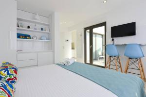 a white bedroom with a bed and two blue chairs at Ivy Apartments in Zadar